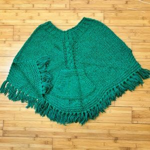 Hand knit fringed girl’s poncho. Cables centered on front and back, front pouch.